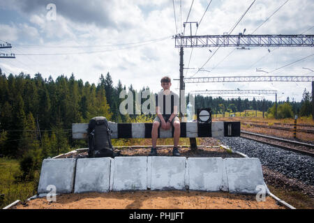 La gare ferroviaire sur l'adolescent assis avec baclpack Banque D'Images