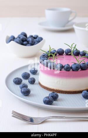 Les deux couleurs mini bleuets gâteau au fromage. Sans cuisson ronde cheesecake, bol avec les bleuets, tasse de café et un bol de sucre. Haut de gâteau décoré par Banque D'Images