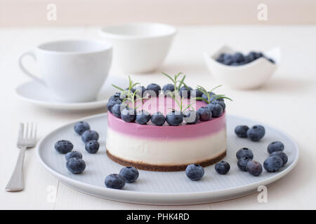 Les deux couleurs mini bleuets gâteau au fromage. Sans cuisson ronde cheesecake, bol avec les bleuets, tasse de café et un bol de sucre. Haut de gâteau décoré par Banque D'Images