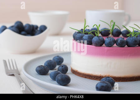 Les deux couleurs mini bleuets gâteau au fromage. Sans cuisson ronde cheesecake, bol avec les bleuets, tasse de café et un bol de sucre. Haut de gâteau décoré par Banque D'Images