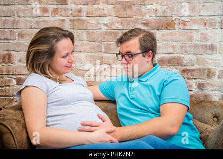 Belle femme enceinte et l'homme assis près de wall Banque D'Images