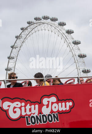 Les touristes et les visiteurs sur le pont supérieur d'un bus de Londres avec le London eye en arrière-plan. Banque D'Images