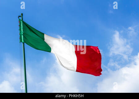 En agitant le drapeau italien contre le ciel bleu Banque D'Images