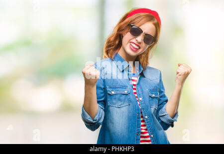 Belle jeune femme de plus fond isolé portant des lunettes de soleil très heureux et excité de faire geste gagnant avec bras levés, sourire et crier Banque D'Images