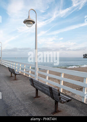 Deux bancs en bois sur le quai donnant sur la plage avec un ciel nuageux Banque D'Images