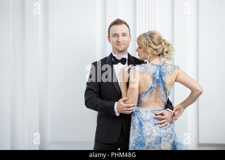 Beau jeune couple dans le luxe des vêtements à la mode hugging indoors Banque D'Images