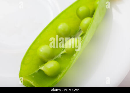 Open Green pea pod sur la plaque blanche. close-up Banque D'Images