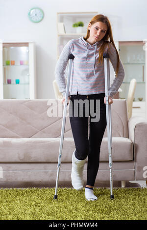 Jeune femme avec jambe cassée à la maison Banque D'Images