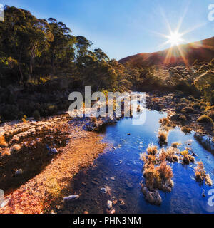 Bright rising sun in Snowy River national park se reflétant dans des flaques d'encore couverts de givre Snowy River en saison d'hiver. Banque D'Images