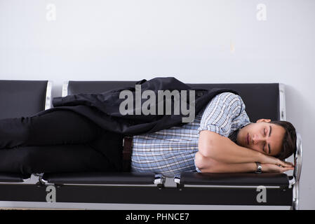 L'homme de dormir sur les chaises dans l'aéroport Banque D'Images