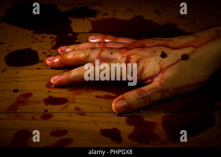 Meurtre, suicide ou de scène de crime. Main d'une personne morte imbibé de sang sur le plancher. Banque D'Images