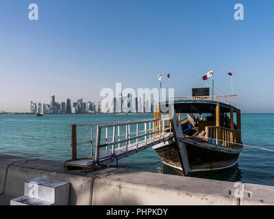 DOHA, QATAR - Dec 2018 : Échelle de Corniche sur Broadway bateau traditionnel en bois du golfe d'inviter à tour touristique de la ville. Belle vue sur la ville de Doha avec Qatar flottante avec des drapeaux. Le Qatar, au Moyen-Orient Banque D'Images