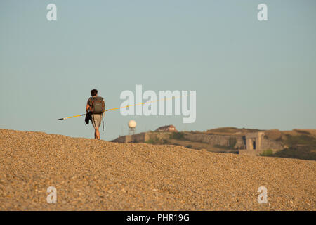 Un pêcheur de maquereau en direction de la maison en fin d'après-midi sur la plage de Chesil avec l'Île de Portland derrière. Dorset England UK GO Banque D'Images