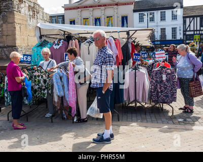 Un groupe de dames shopping pour les robes à Ripon Yorkshire du Nord du marché alors qu'un homme attend patiemment Banque D'Images