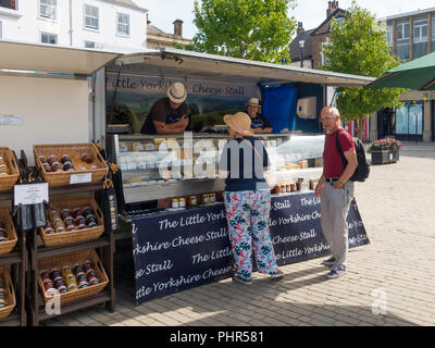 Un homme et une femme chat avec des marchands sur le petit fromage à Ripon Yorkshire décrochage marché North Yorkshire England UK Banque D'Images