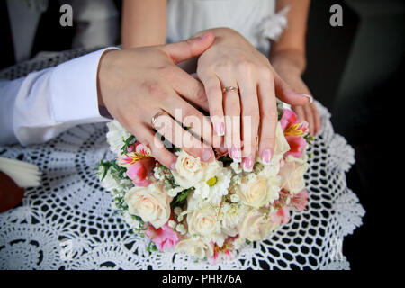 Mains de l'époux et épouse sur le bouquet de mariée Banque D'Images