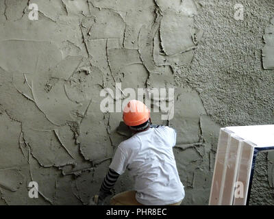 Les travailleurs de la construction du mur à l'aide de plâtre ciment plâtre sur le chantier de construction. Ils portent des équipements de protection appropriés pour prévenir les mauvais cas. Banque D'Images