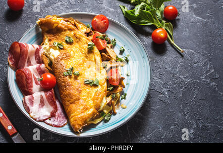 Omelette aux tomates, champignons et bacon. Petit déjeuner sur fond de pierre. Alimentation saine. Banque D'Images