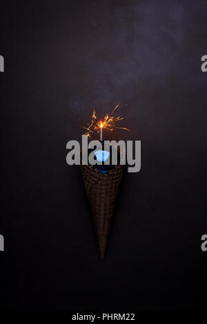 Black Ice Cream Cone avec boule brillant bleu et la gravure bougie sparcler sur fond blanc, style monochrome partie libre minimale Banque D'Images