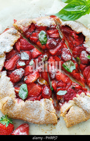 Gâteau de forme libre (galette) avec des fraises et du basilic. Banque D'Images