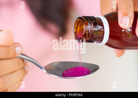 Woman pouring médicament antipyrétique ou érable du biberon à la cuillère. Santé, médecine et concept. Banque D'Images