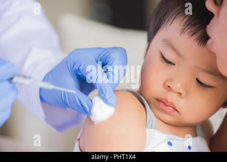 Médecin pour faire une injection de vaccin pour une fille. Petite fille pleurer avec sa mère sur l'arrière-plan. Banque D'Images