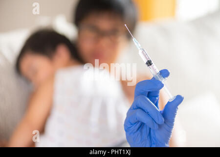 Médecin pour faire une injection de vaccin pour une fille. Petite fille avec sa mère sur l'arrière-plan. Banque D'Images