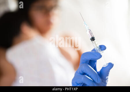 Médecin pour faire une injection de vaccin pour une fille. Petite fille avec sa mère sur l'arrière-plan. Banque D'Images