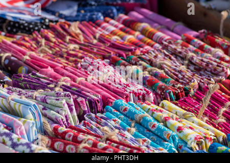 Une sélection de multi-couleur lin ou coton plaids et Chiffons en vente sur un rack dans une échoppe de marché la vente de linge de maison coloré. Banque D'Images