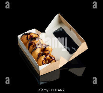 Quatre des donuts avec garniture au chocolat emballé dans la boîte noire sur papier Banque D'Images