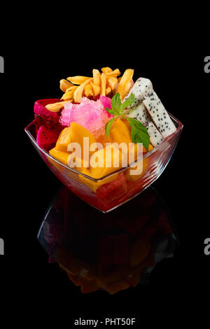 Bol en verre salade de fruits sur fond noir Banque D'Images