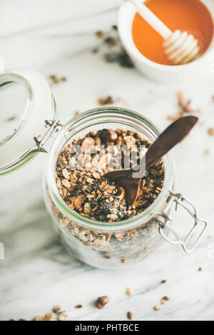 Petit-déjeuner sain préparation. Le sarrasin et granola chocolat aux noisettes dans un bocal en verre sur la lumière en arrière-plan, Vue de dessus. Manger végétalien, propre Banque D'Images