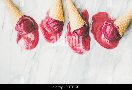 Dessert d'été frais. Télévision à jeter de la fonte de glace sorbet framboise naturel cuillers-doux dans plus de cônes alvéolés en arrière-plan, Vue de dessus, copy space Banque D'Images