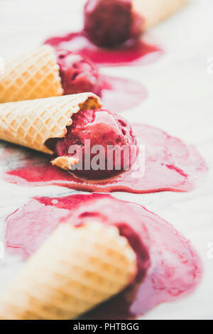 Dessert d'été frais. Naturel de fusion sorbet framboise glace boules à cônes alvéolés doux plus en arrière-plan, selective focus. S végétalien sain Banque D'Images