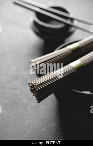 Nouilles Soba, bateau à vapeur de bambou et une cuisine asiatique props sur fond sombre Banque D'Images