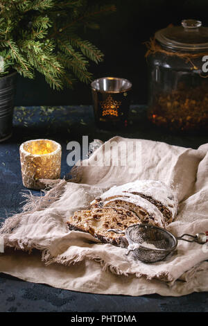 Tranches de gâteau de Noël traditionnel allemand, cuisson festive. Les stollen avec raisins secs et le sucre en poudre sur le linge de table serviette sur bleu foncé avec fir Banque D'Images