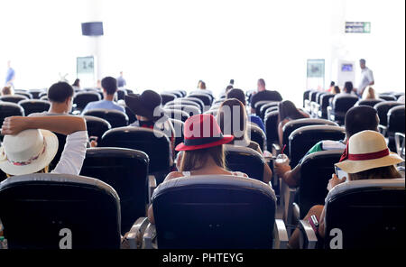 Passagers attendent sur des bancs pour le départ à l'aéroport. Banque D'Images