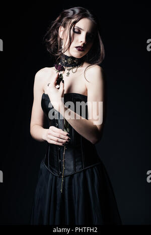 Portrait dramatique de la belle triste goth girl holding a withered rose dans les mains Banque D'Images