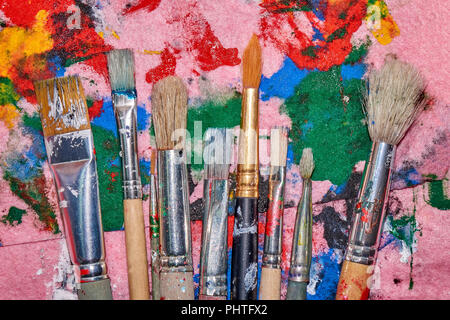 Neuf balais usés de différentes tailles sur la palette de rose coloré malpropre fond artistique Banque D'Images