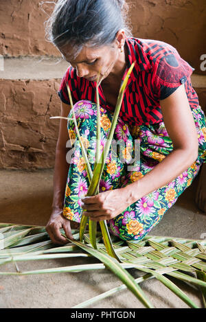 Portrait d'une dame verticale le tissage de feuilles de palmier. Banque D'Images