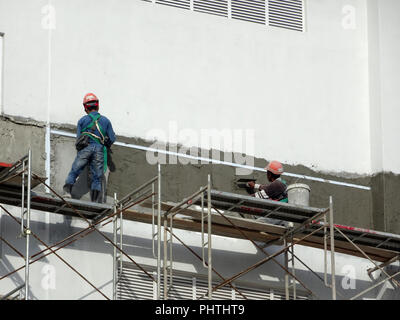 Les travailleurs de la construction du mur à l'aide de plâtre ciment plâtre sur le chantier de construction. Ils portent des équipements de protection appropriés pour prévenir les mauvais se produire Banque D'Images