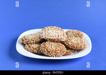 Biscuits aux graines de sésame dans une assiette blanche sur un fond violet. Close up Banque D'Images