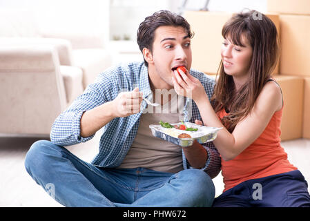 Jeune famille de manger des aliments dans nouvel appartement après déménagement dans Banque D'Images