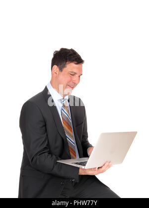 Happy businessman sitting avec son ordinateur portable Banque D'Images