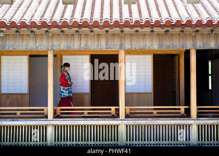 Un employé portant des vêtements traditionnels promenades le long du couloir à l'extérieur de l'Sasunoma, qui est situé à l'intérieur des terres de Château Shuri à Naha, Okina Banque D'Images