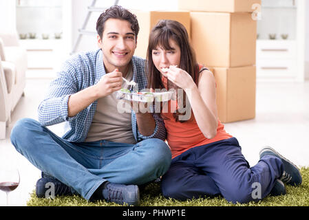 Jeune famille de manger des aliments dans nouvel appartement après déménagement dans Banque D'Images