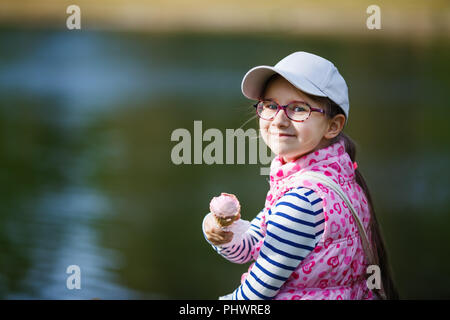 Smiling little Girl with ice-cream en mains à l'extérieur. Banque D'Images