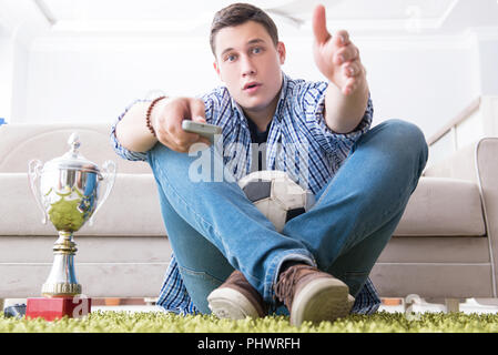 Jeune homme étudiant regarder le football à la maison Banque D'Images