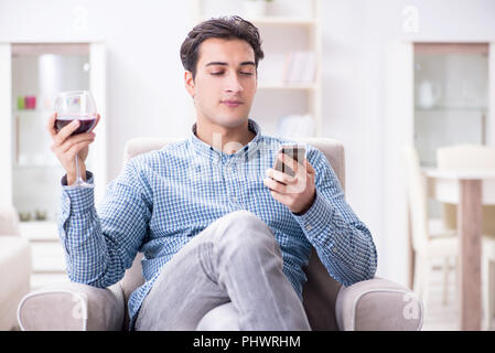 Young man drinking wine at home Banque D'Images
