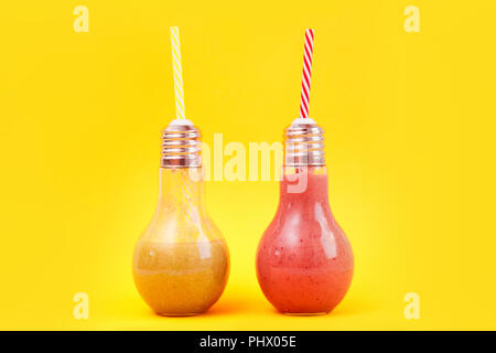 Deux pots en forme de lampe avec smoothies aux fruits isolé sur fond jaune. Banque D'Images